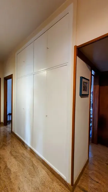 Armadio a muro laccato bianco a tutta altezza, lungo un corridoio